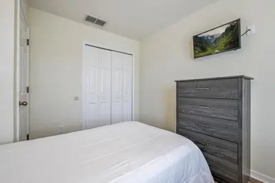 a bedroom with a white bed and a dresser at Remodeled Gem - Comfort & Location in Kissimmee