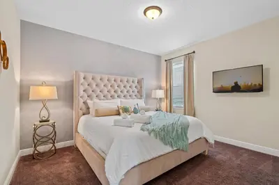 a white bedroom with a large bed with a large headboard at 8 Bd home with Themed rooms and Pool 2308 in Orlando