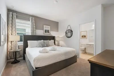 a bedroom with a large bed and a bathroom at Spacious Family Reunion 15BR Home Pool Spa Game Rm in Kissimmee