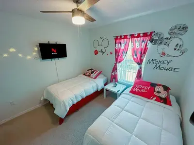 a bedroom with two beds and a flat screen tv at Roomy House Near Disney with Resort Pool and Patio BBQ in Kissimmee