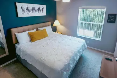 a bedroom with a white bed with a blue wall at Roomy House Near Disney with Resort Pool and Patio BBQ in Kissimmee