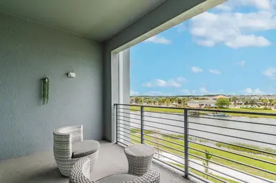 a balcony with two chairs and a large window at Storey Lake: Apartment with lake view in Kissimmee