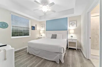 a white bedroom with a large bed and a window at Storey Lake: Apartment with lake view in Kissimmee