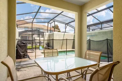a glass house with a table and chairs on a patio at Home with a pool at Storey Lake Resort in Kissimmee