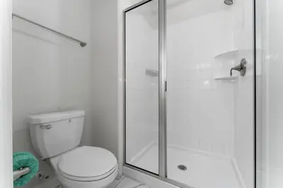 a white bathroom with a toilet and a shower at Townhome with pool at Storey Lake in Kissimmee