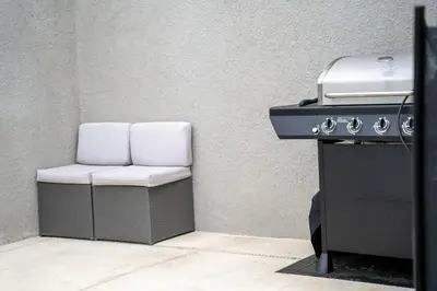 a grill with white cushions sitting next to a wall at Townhome with pool at Storey Lake in Kissimmee