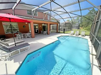 a swimming pool with a patio and an umbrella at Golden Beach Villa home in Kissimmee