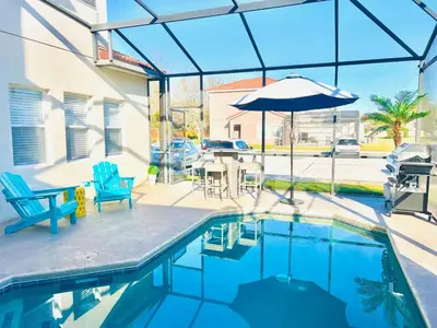 a swimming pool with a table and an umbrella at Remarkable Cozy 4Bed-3Ba Townhouse in Kissimmee