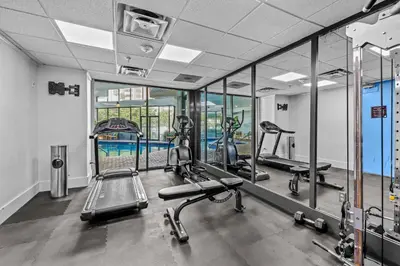 a gym with several tread machines and mirrors at Apartment with Volcano Bay view in Orlando