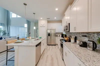 a large kitchen with white cabinets and marble counter tops at Luxury 5BR Home, Private Pool, Prime Location in Kissimmee