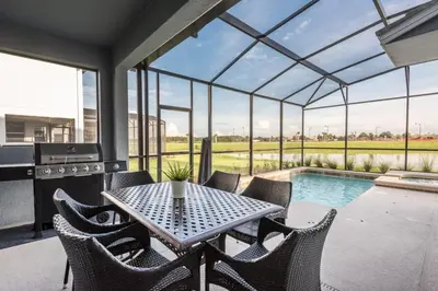 a patio with a table and chairs and a swimming pool at Luxury 5BR Home, Private Pool, Prime Location in Kissimmee