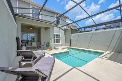 a swimming pool with two chairs and a house at Cozy Home Near Disney Parks - Prime Location in Kissimmee