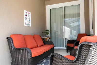 a living room with an orange couch and two chairs at Vibrant Themed Home Prime Location in Kissimmee
