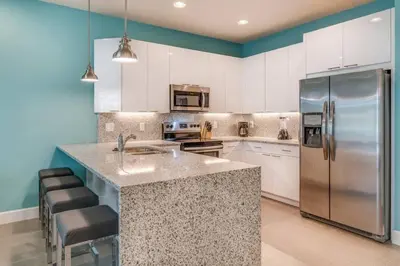 a kitchen with white cabinets and a stainless steel refrigerator at Cozy Villa Private Pool Prime Spot in Orlando