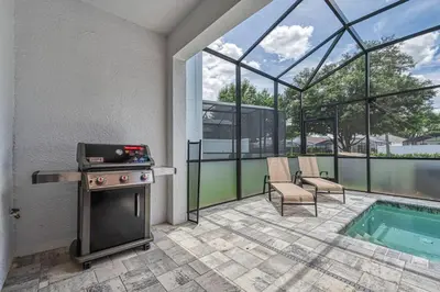 a patio with a grill and a swimming pool at Modern Luxury Retreat - Mickey & Harry Potter Beds in Orlando