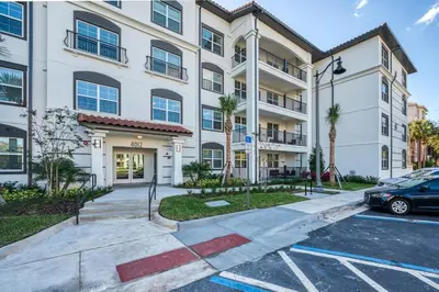 a building with a car parked in a parking lot at Prime Location-Spacious Condo for 8 Guests in Orlando
