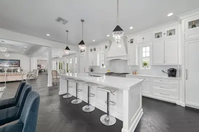 a kitchen with white cabinets and a island with bar stools at Celebration FL 34747 in Orlando