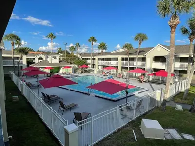 a swimming pool with red umbrellas and a resort at Newly renovated room in cozy hotel near Disney 2 in Kissimmee