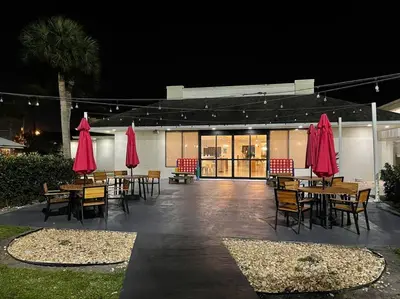 a patio with tables and chairs and red umbrellas at Newly renovated room in cozy hotel near Disney 2 in Kissimmee