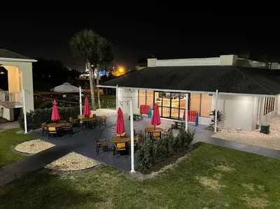 a group of tables and chairs with umbrellas at night at Newly renovated room in cozy hotel near Disney 2 in Kissimmee
