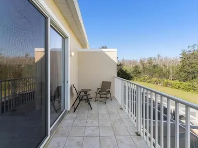 a patio with two chairs and a table on a balcony at Priceless Peace at Serenity by Shine Villas, 081 townhouse in Orlando