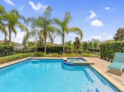 a swimming pool with a blue chair and palm trees at Gorgeous Remo 8 BR at Encore Resort next to Disney in Orlando
