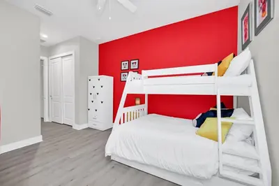 a bedroom with a red wall and a bunk bed at Magical Residence Resort, 5 min Disney in Orlando