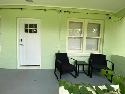 a patio with two chairs and a table and a door at Totally 80s! in Sanford