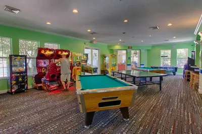 a boy standing in a games room with pool tables at Windsor Palms, next to clubhouse in Kissimmee