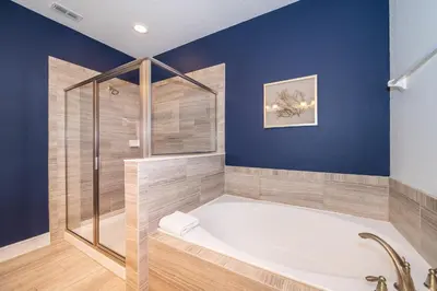 a bathroom with a tub and a glass shower at EPIC Disney 10Min Retreat, 8BR Resort Villa and Arcade in Orlando