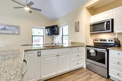 a kitchen with white cabinets and a washer and dryer at St Cloud Vacation Rental - Walk to Lakefront Park! in Saint Cloud