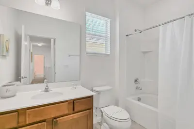 a white bathroom with a toilet and a sink and a tub at Modern 6BR Home - Pool Games BBQ - Near Disney in Kissimmee