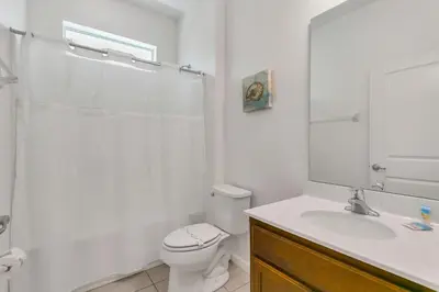 a white bathroom with a toilet and a sink at Modern 6BR Home - Pool Games BBQ - Near Disney in Kissimmee