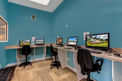 an office with four computer desks with computers on them at Modern 6BR Home - Pool Games BBQ - Near Disney in Kissimmee