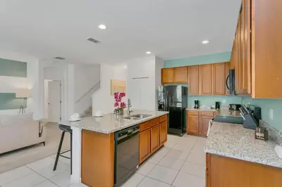 a large kitchen with wooden cabinets and a counter top at Modern 6BR Home - Pool Games BBQ - Near Disney in Kissimmee