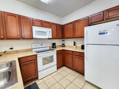 a kitchen with wooden cabinets and a white refrigerator at Retreat at Secret Lake 10 mins to Disney in Kissimmee