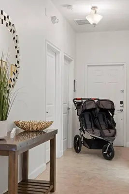 a stroller in a room with a table and a mirror at Storey Lake Townhome fun for families at Remy's Retreat in Kissimmee