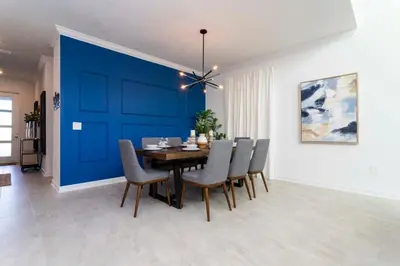 a dining room with a blue wall and a table and chairs at Super Luxury Modern Home, Prime Location in Kissimmee