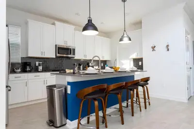 a kitchen with white cabinets and a blue island with bar stools at Super Luxury Modern Home, Prime Location in Kissimmee