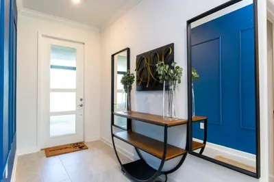 a hallway with a blue door and a table with flowers at Super Luxury Modern Home, Prime Location in Kissimmee