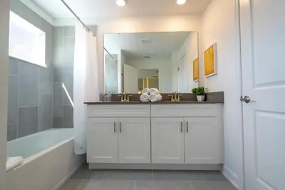 a bathroom with a sink and a tub and a mirror at WonderFul 4Bd w Pool Close to Disney at StoreyLake 2669 in Kissimmee