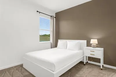 a white bedroom with a white bed and a window at Upstay Ultimate Orlando Retreat w Pool & Hot Tub Sleeps 16 in Kissimmee