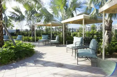 a patio with chairs and umbrellas and palm trees at Elegant Apartment 3BR2BA • Near Disney • PoolLazy River at Storey Lake Resort SL47318 in Kissimmee