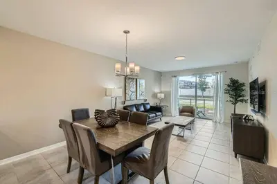 a dining room with a table and a living room at Modern Apartment 2BR2BA • Near Disney • Storey Lake Resort SL47314 in Kissimmee