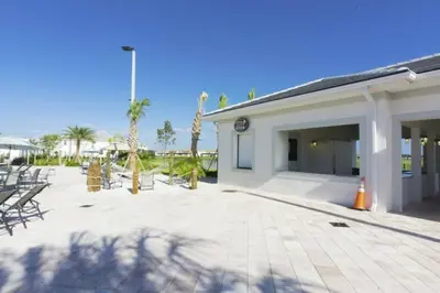 a building with a patio with chairs and palm trees at Premium 5BE4BA Home with Private Pool and Game Room Storey Lake Resort SL4839 in Kissimmee