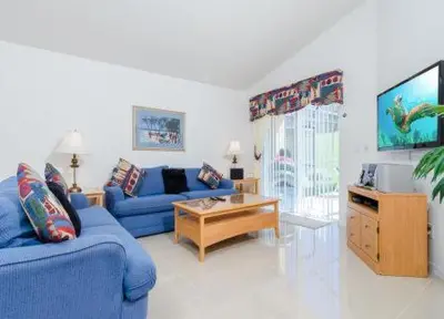 a living room with a blue couch and a tv at Emerald Island Kissimmee in Kissimmee