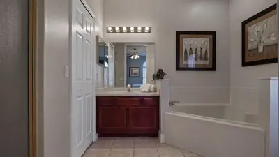 a bathroom with a tub and a sink and a mirror at Tranquil Formosa Gardens Villa in Orlando