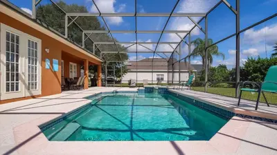 a swimming pool with blue chairs next to a house at Tranquil Formosa Gardens Villa in Orlando