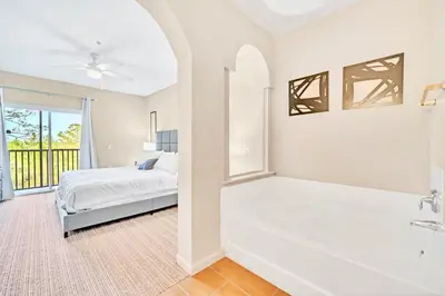 a bedroom with a tub and a bed and a window at Near Disney - 2BR Condo - Balcony Pool in Orlando