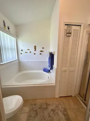 a white bathroom with a tub and a toilet at Private pool with a beautiful view overlooking the lake! Near Disney - Universal in Kissimmee